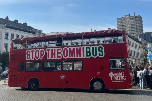 Ein roter Bus mit der Aufschrift Stop the Omnibus steht in Brüssel auf einer Straße.